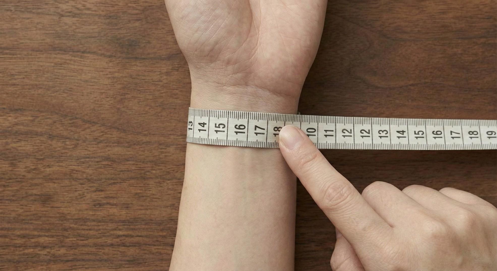 Detailed view of reading the overlap point on a soft measuring tape for wrist size.