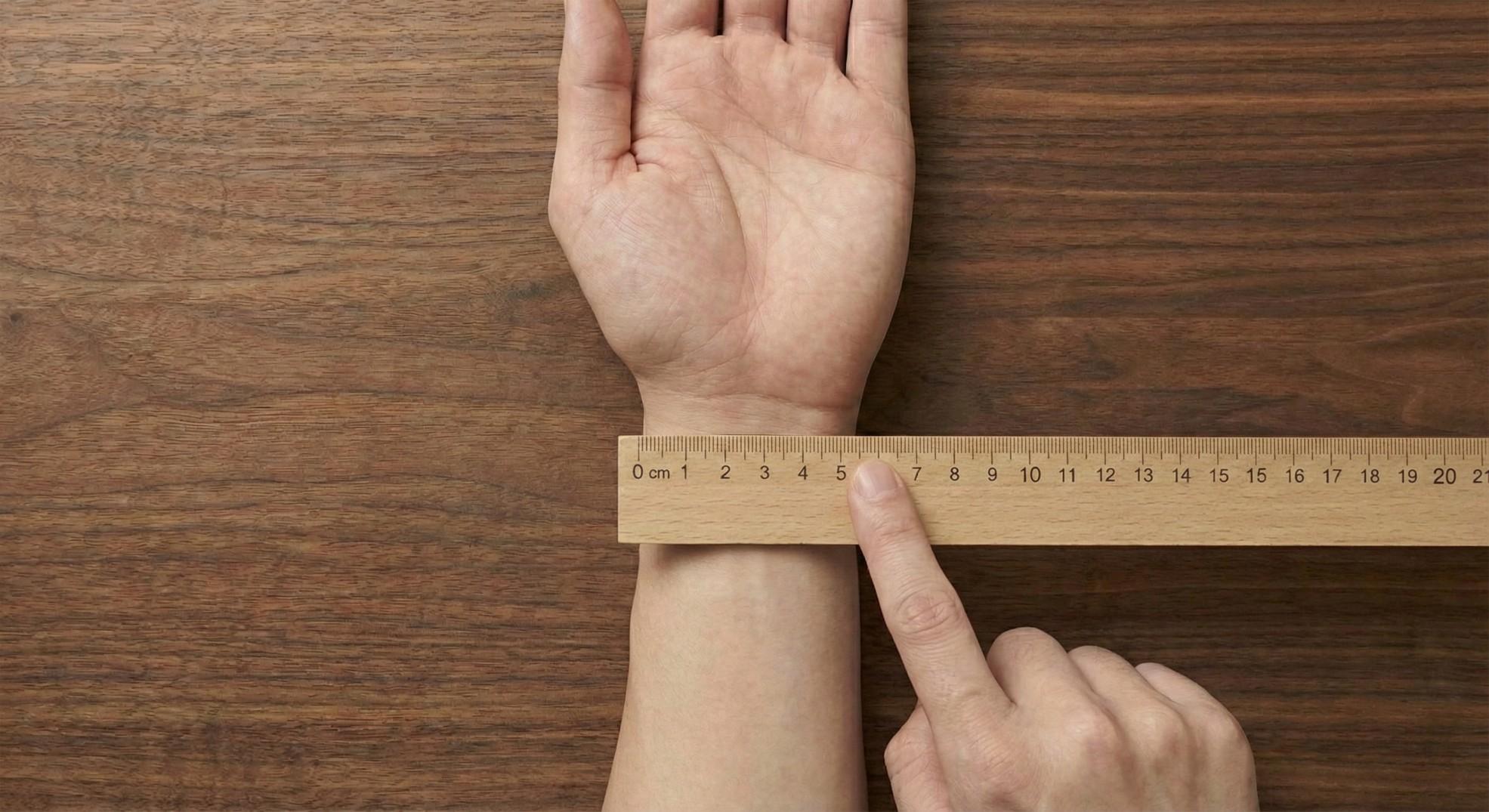 Close-up view of measuring the top width of a wrist with a ruler, showing a typical measurement line.